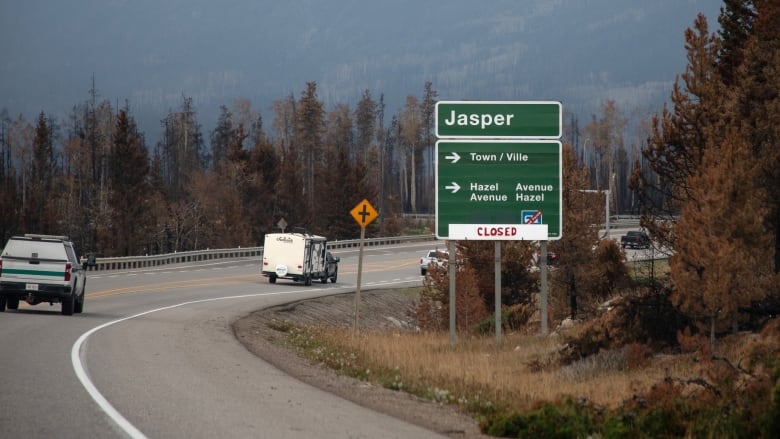 Cars are pictured on a road along a sign that reads Jasper.