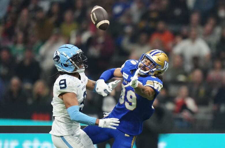 Opposing football players challenge for the ball.