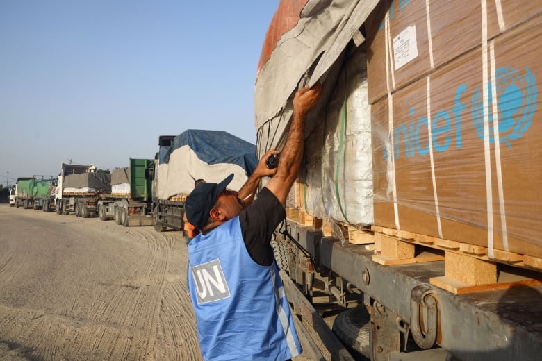 A man with a blue UN vests checks truck.