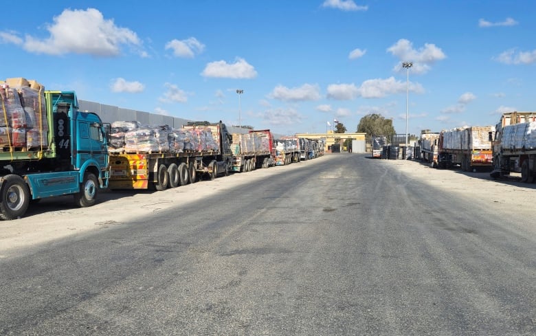 Trucks carrying aid lined up on the side of the street.