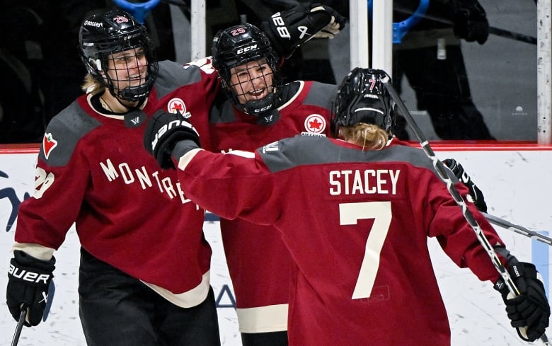 Three hockey players celebrate on ice together.