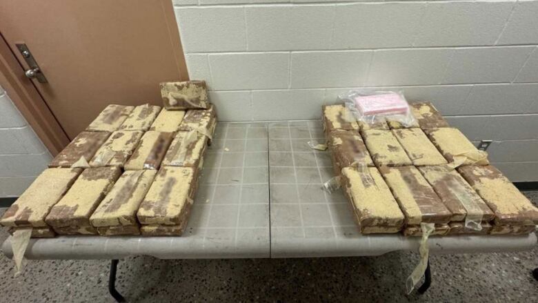 Several dozen bricks of seized cocaine lying on a table in the custody of the RCMP. 