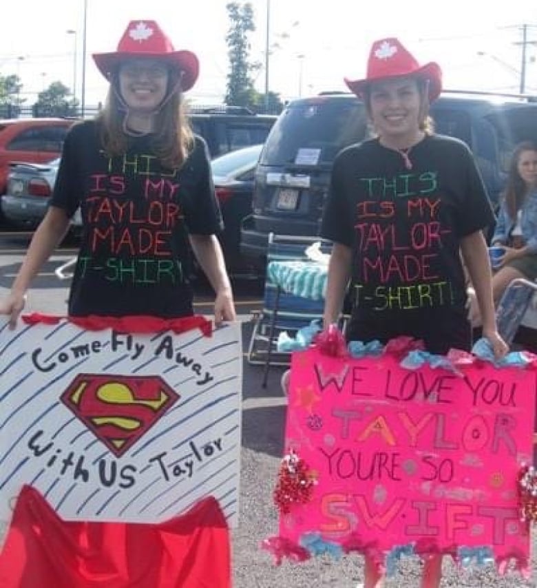 Two girls in cowboy hats holding Taylor Swift homemade posters