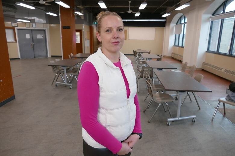 A woman on a pink sweater stands in front of a room. 