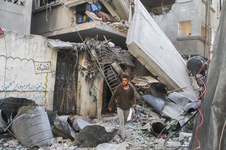 A man walks next to rubble.