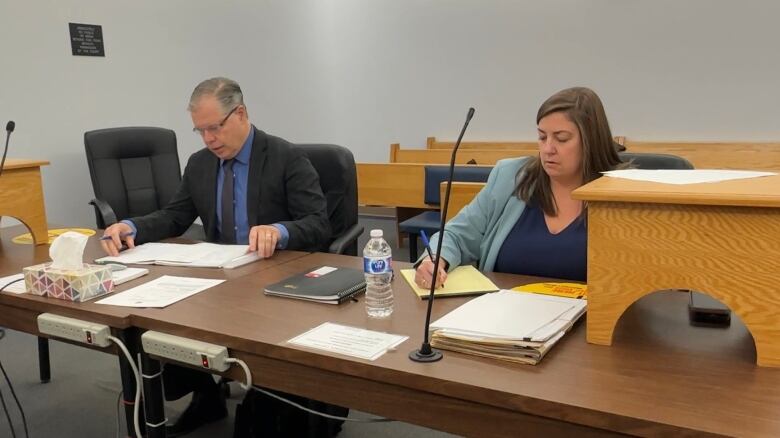 A man and woman sitting at a bench in a courtroom.