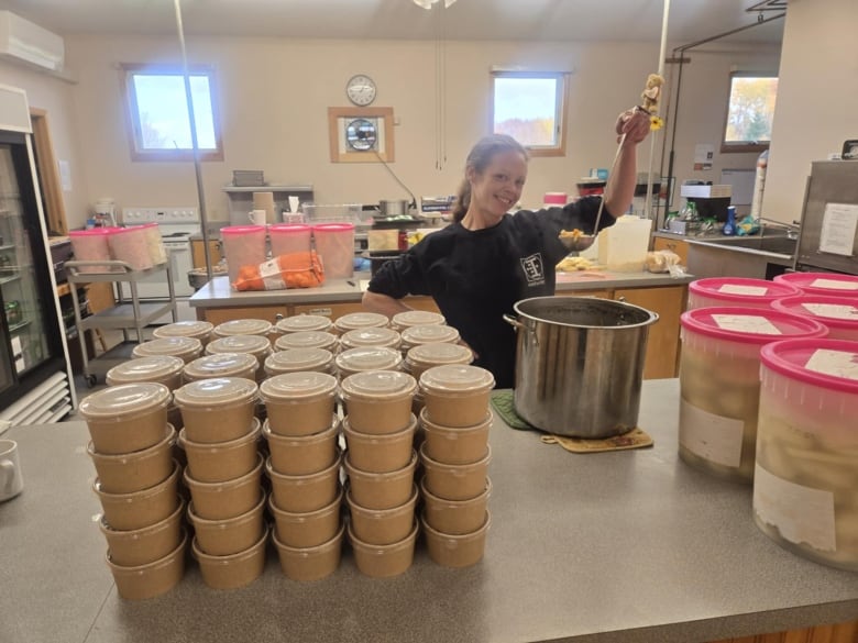 A woman stands with many takeout containers in a kitchen 