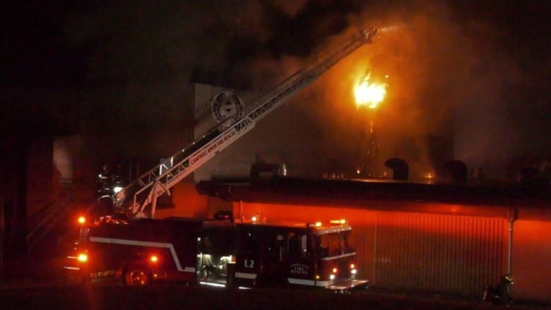 A firetruck outside a burning building.