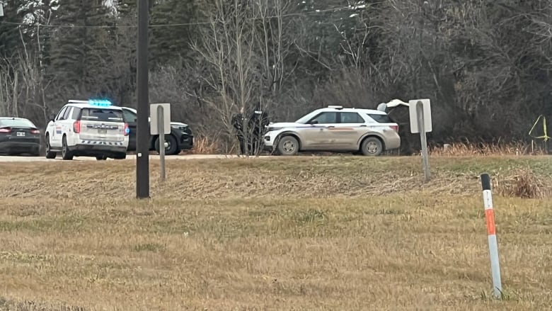 Several police vehicles are seen on a rural road.