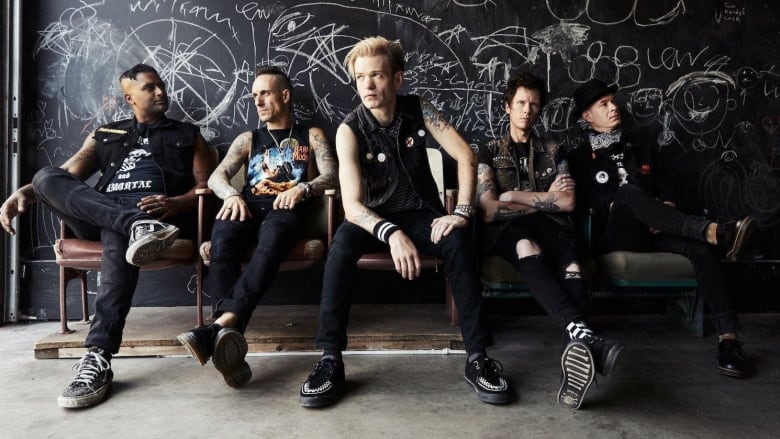 Sum 41 sits on a black couch with the members looking in different directions.