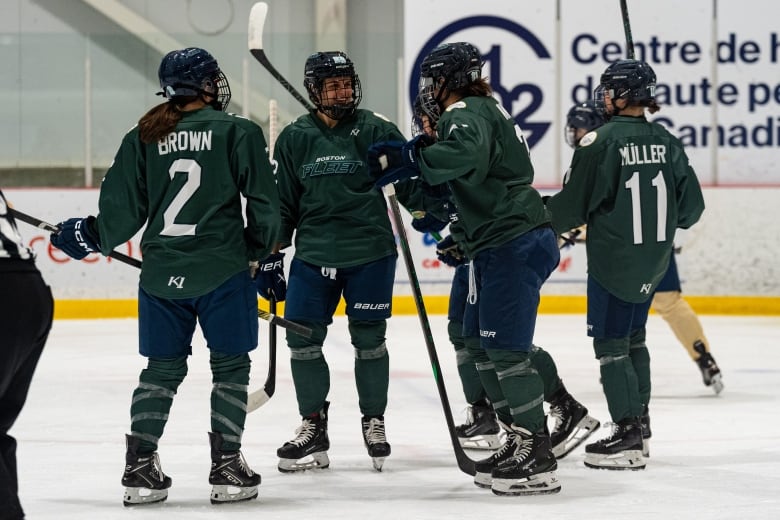 Several hockey players in green jerseys that say Fleet on them celebrate on the ice.