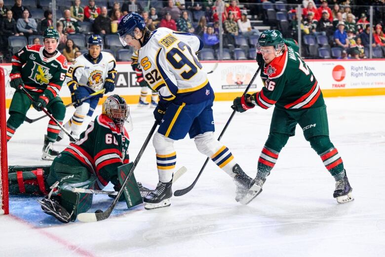 A goalie stretches their leg out to make a save against an opponent.