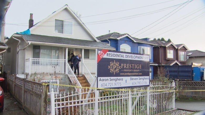 A home with crime tape around it and a 'for sale' sign.