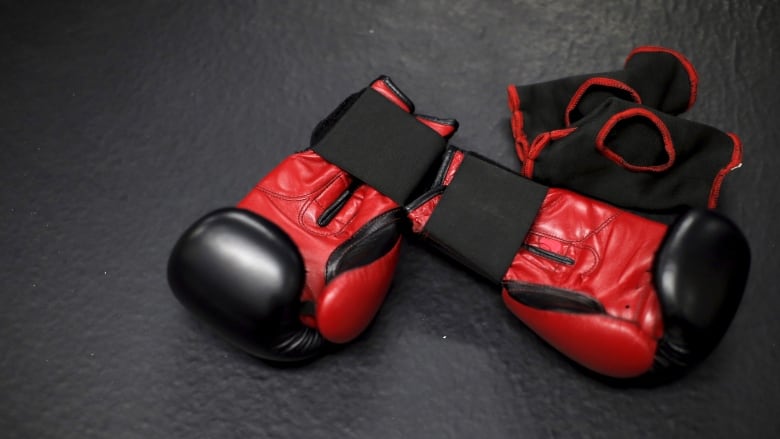 A pair of red gloves lie on a mat.